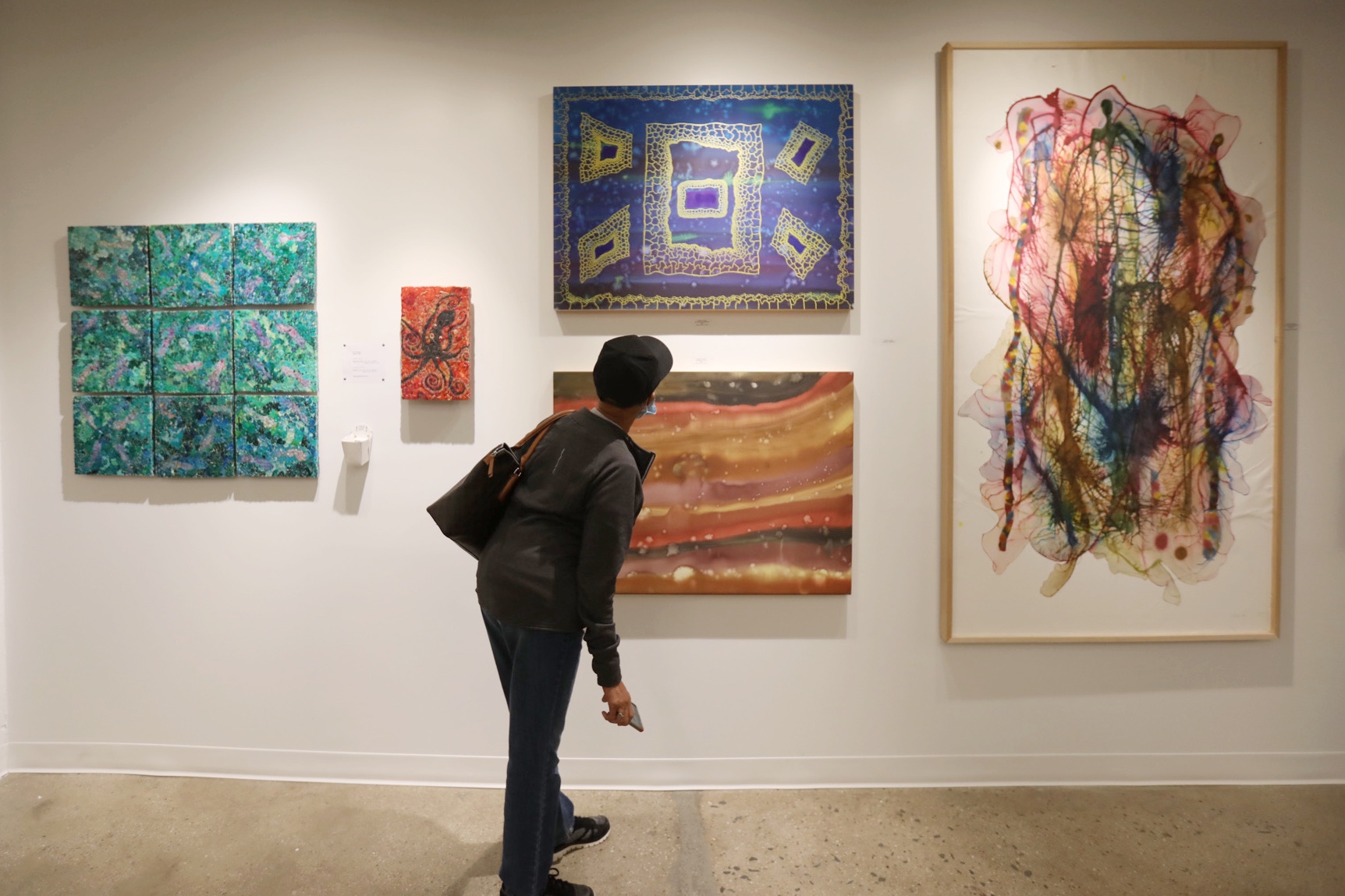 artist Debasish Sinha discusses his artwork with a visitor in his studio with small still life and landscape paintings on the wall in the background