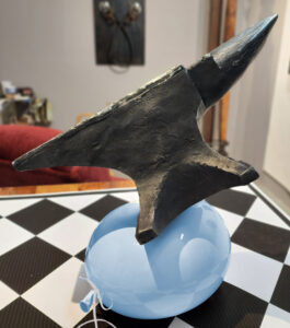 Sculpture of an anvil resting on top of a light blue balloon