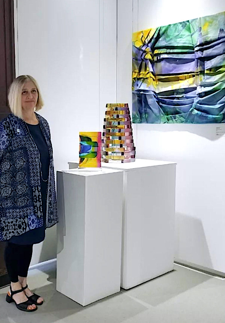 Christine Barney stands next to her glass sculpture on a pedestal